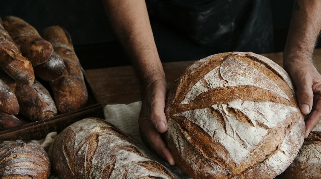 Άτομο κρατά καρβέλι ψωμί στα χέρια του
