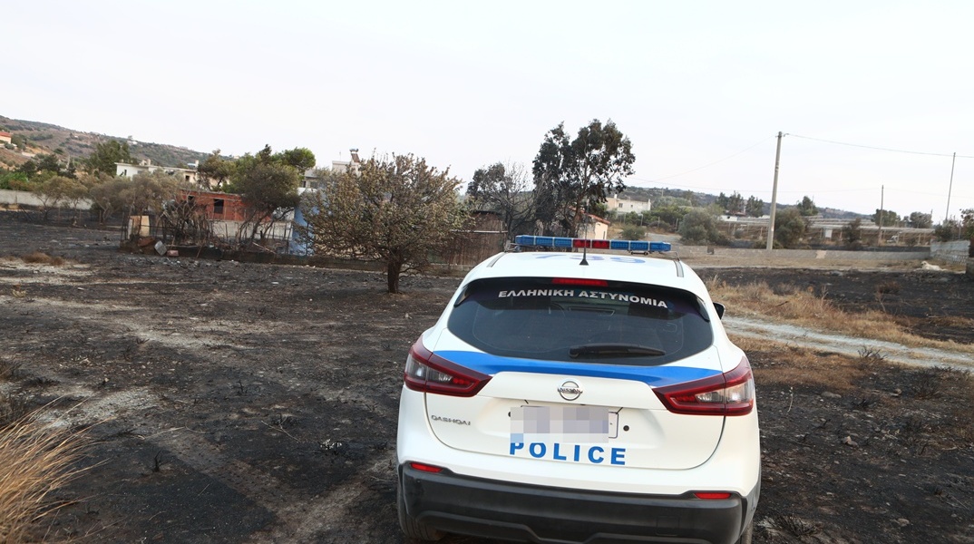 Περιπολικό της ΕΛ.ΑΣ. σε σημείο όπου έχει καεί από τη φωτιά στην Κερατέα