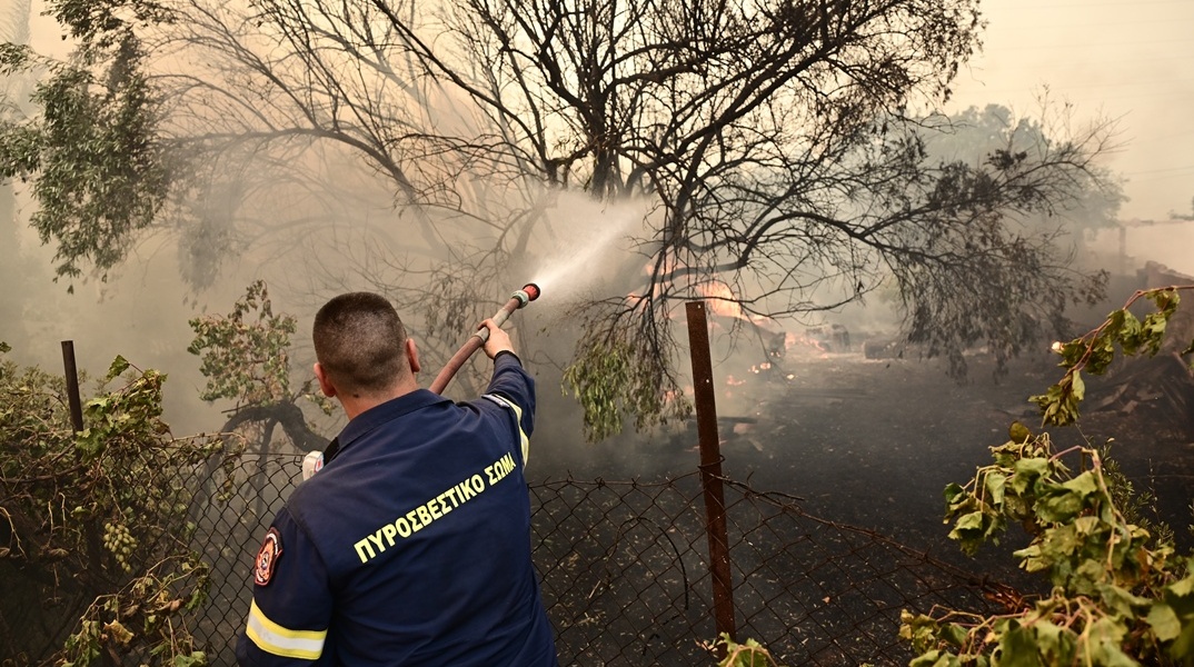 Πυροσβέστης με τη μάνικα ανά χείρας επιχειρεί για την κατάσβεσης φωτιάς