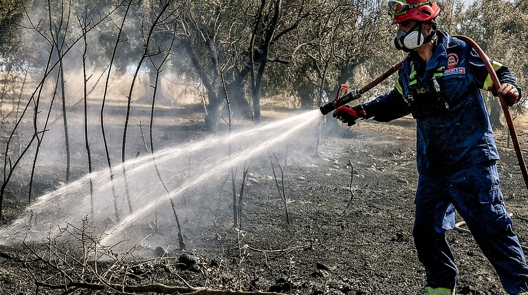 Πυροσβέστης με τη μάνικα ανά χείρας επιχειρεί για την κατάσβεσης φωτιάς