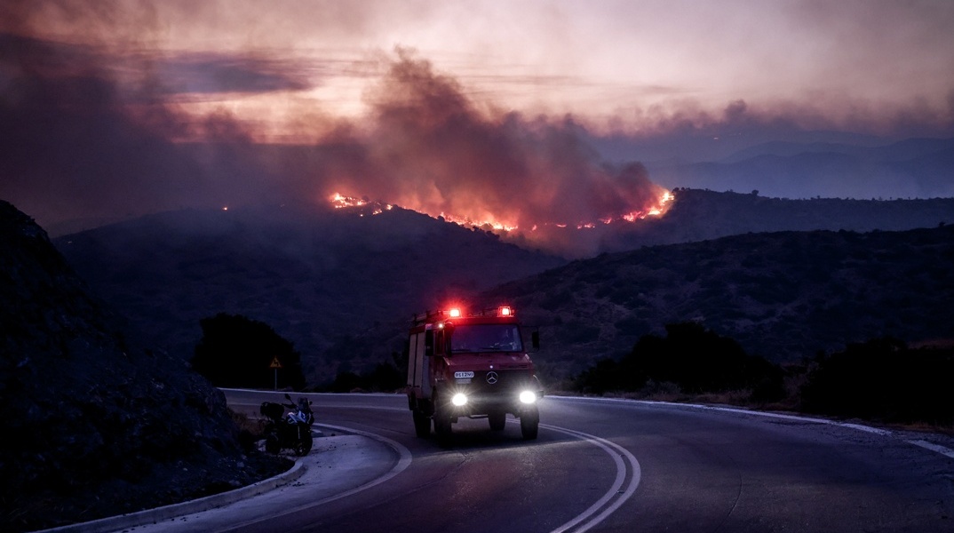 Πυροσβεστικό όχημα με φόντο πύρινο μέτωπο στη Χίο