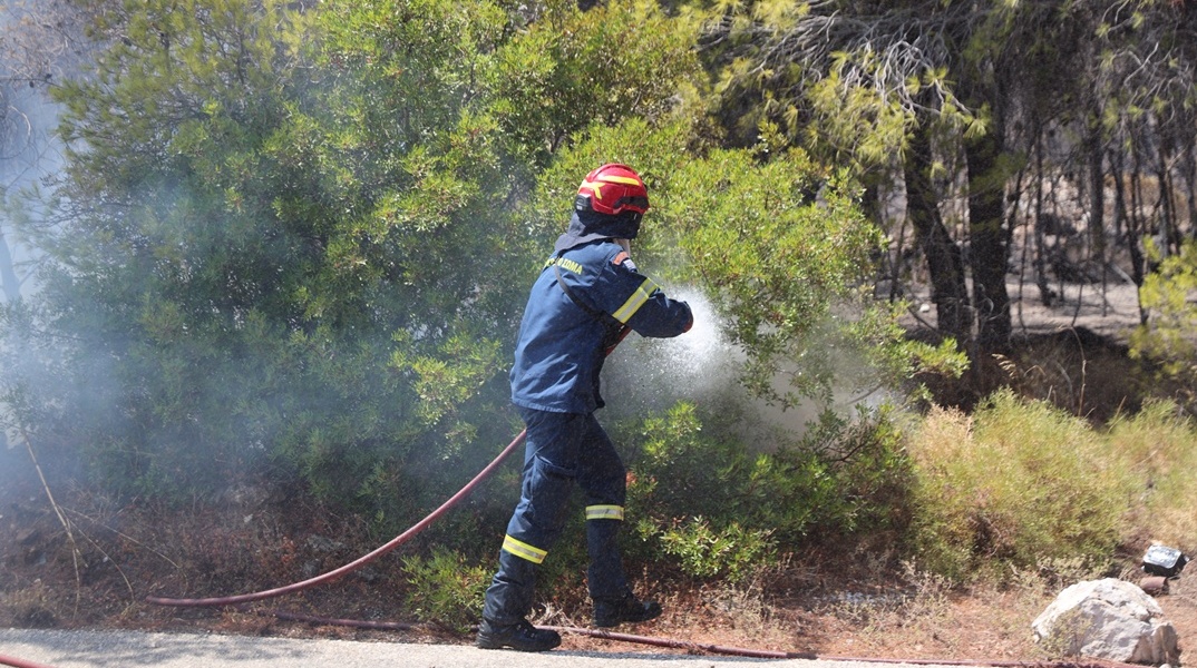 Πυροσβέστης με τη μάνικα ανά χείρας επιχειρεί για την κατάσβεσης φωτιάς