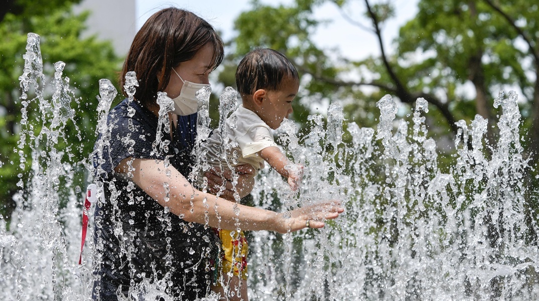 Μητέρα με το παιδί της στο Τόκιο αναζητούν λίγες στιγμές δροσιάς σε σιντριβάνι