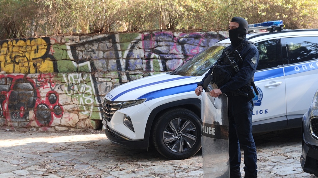 Αστυνομικός με την εξάρτισή του δίπλα από περιπολικό