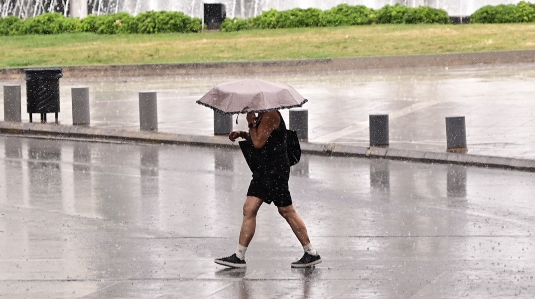 Άτομο με ομπρέλα εν μέσω βροχής στο κέντρο της Αθήνας