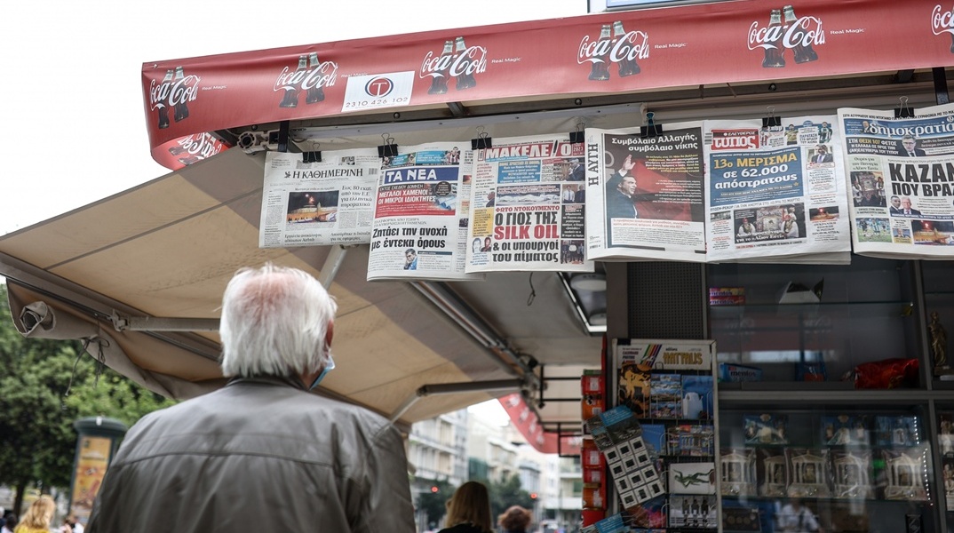 Άνδρας διαβάζει τις εφημερίδες που είναι κρεμασμένες σε περίπτερο