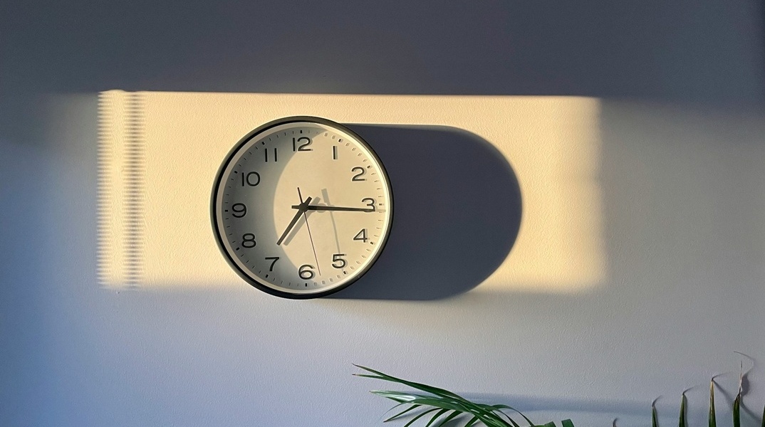 Ρολόι τοίχου που πέφτουν πάνω του ακτίνες του ήλιου