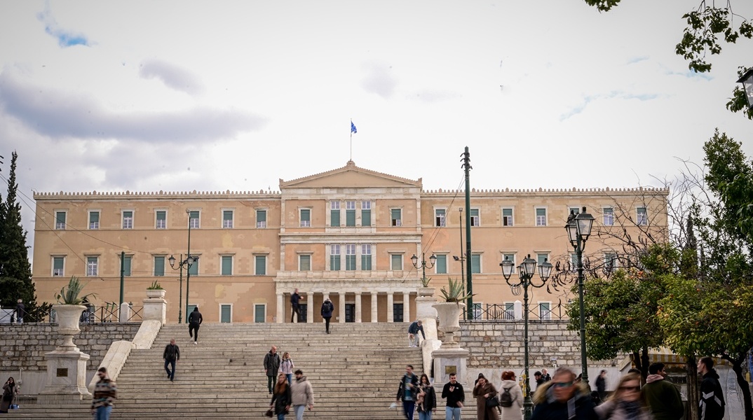 Πολίτες στην πλατεία Συντάγματος με φόντο τη Βουλή