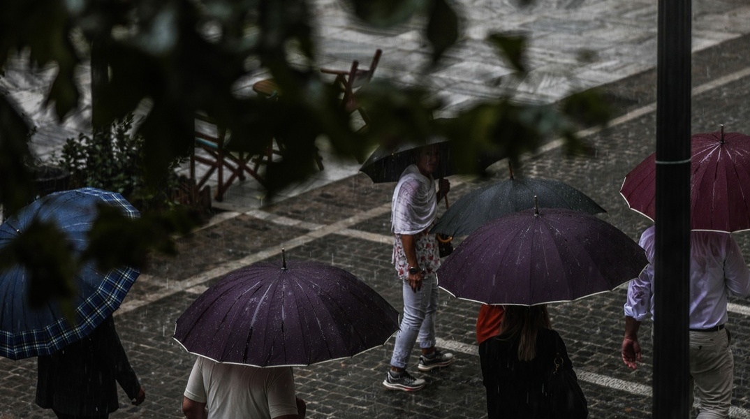Πολίτες με ομπρέλες εν μέσω βροχής