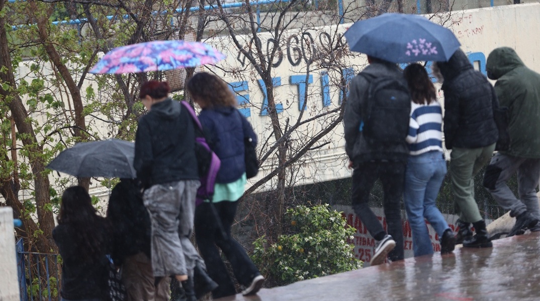 Πολίτες με ομπρέλες εν μέσω βροχής