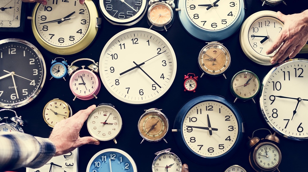 Ρολόγια πολλών σχημάτων και χρωμάτων και χέρια που επιδιώκουν να τα πιάσουν
