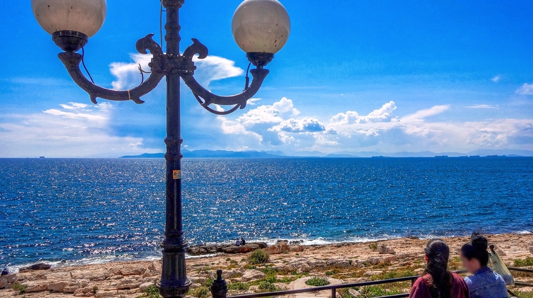 Άτομα σε παγκάκι που κοιτούν τη θάλασσα