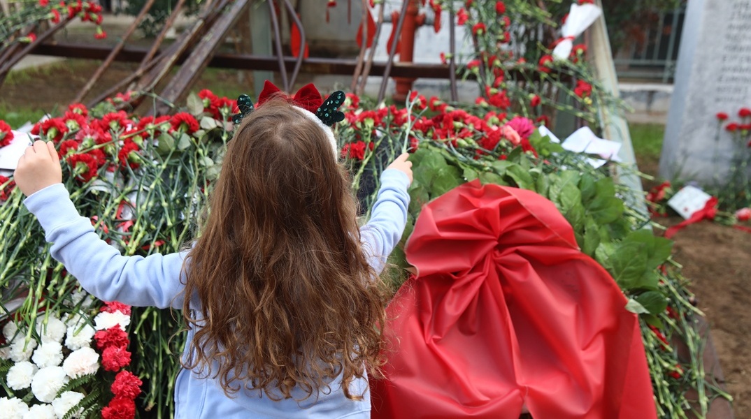 Παιδί αφήνει ένα κόκκινο γαρύφαλλο στο μνημείο για την εξέγρεση του Πολυτεχνείου