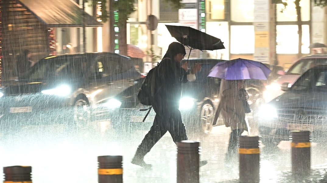 Πολίτες εν μέσω κακοκαιρίας περπατούν σε δρόμο της Αθήνας