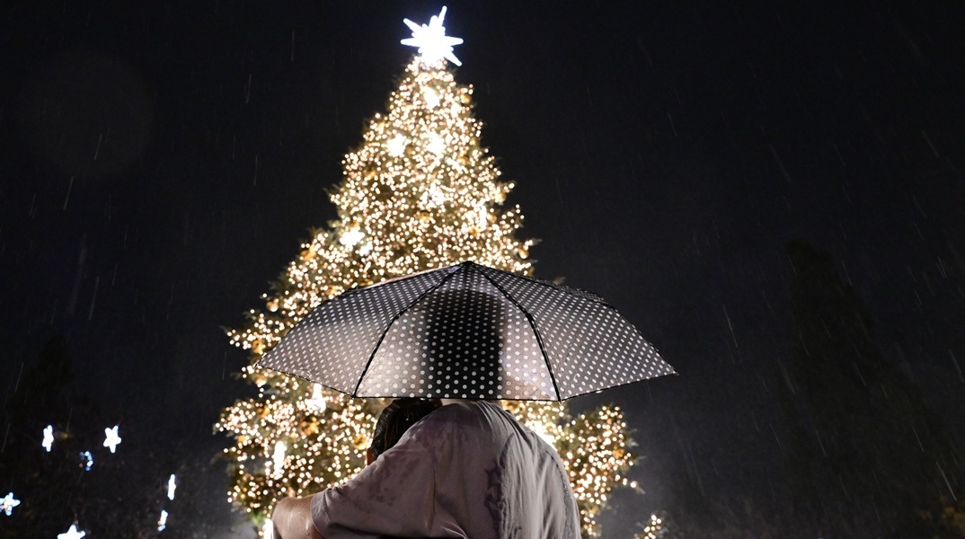 Ζευγάρι κάτω από ομπρέλα κοιτά το χριστουγεννιάτικο δέντρο στην πλατεία Συντάγματος