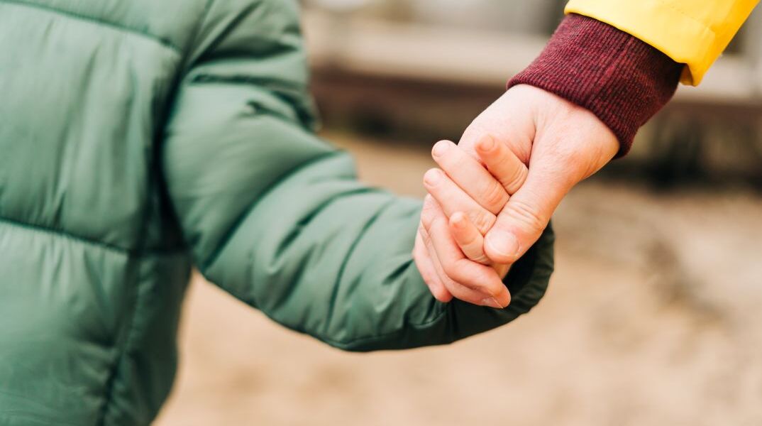 Ένας γονιός που κρατάει το παιδί του από το χέρι