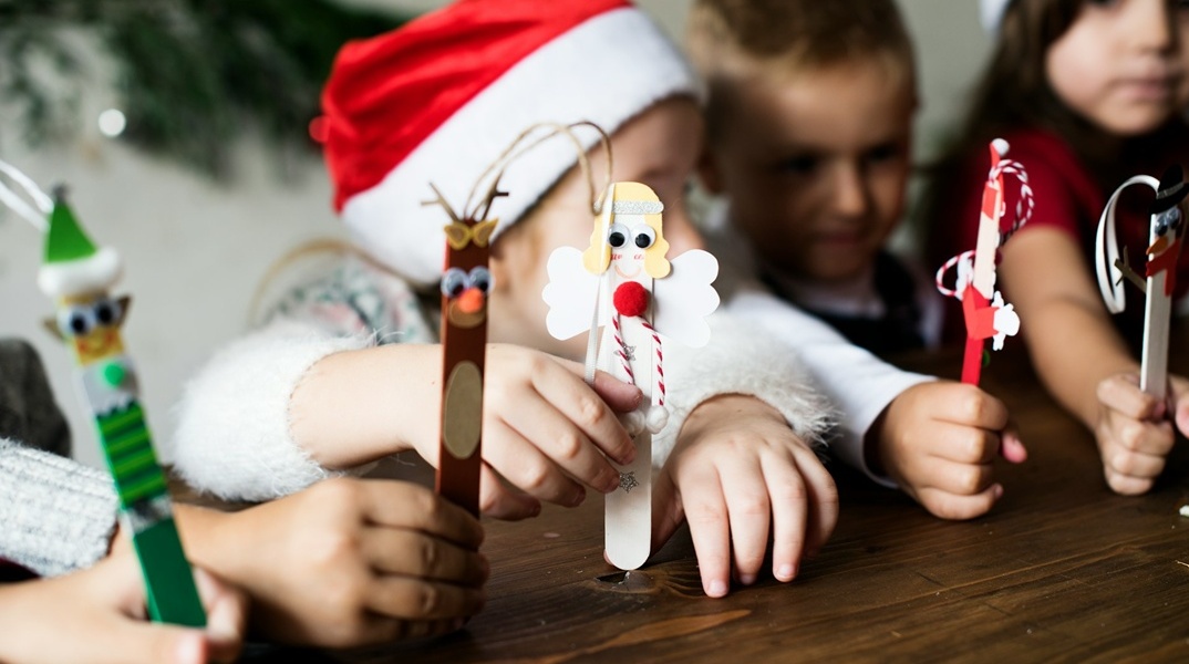 Παιδιά με χριστουγεννιάτικα σκουφιά κρατούν χριστουγεννιάτικα στολίδια