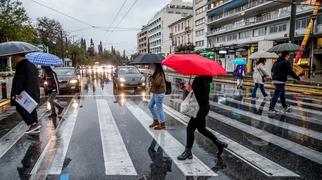 Άτομο περπατούν υπό βροχή χρησιμοποιώντας ομπρέλες