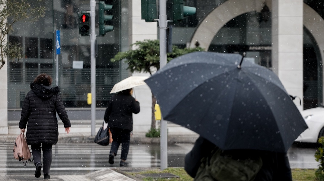 Πολίτες με βαριά ρούχα ενώ ρίχνει απαλό χιόνι