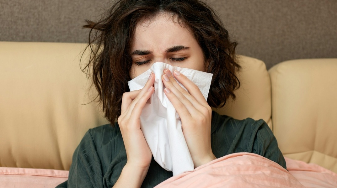 Άτομο σκουπίζει τη μύτη του με χαρτομάντηλα