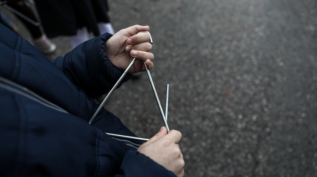 Παιδί που λέει τα κάλαντα με τρίγωνο στο χέρι