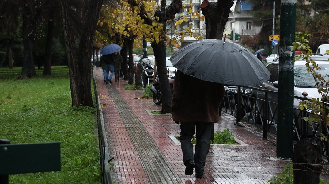 Πολίτες με ομπρέλα εν μέσω βροχής 