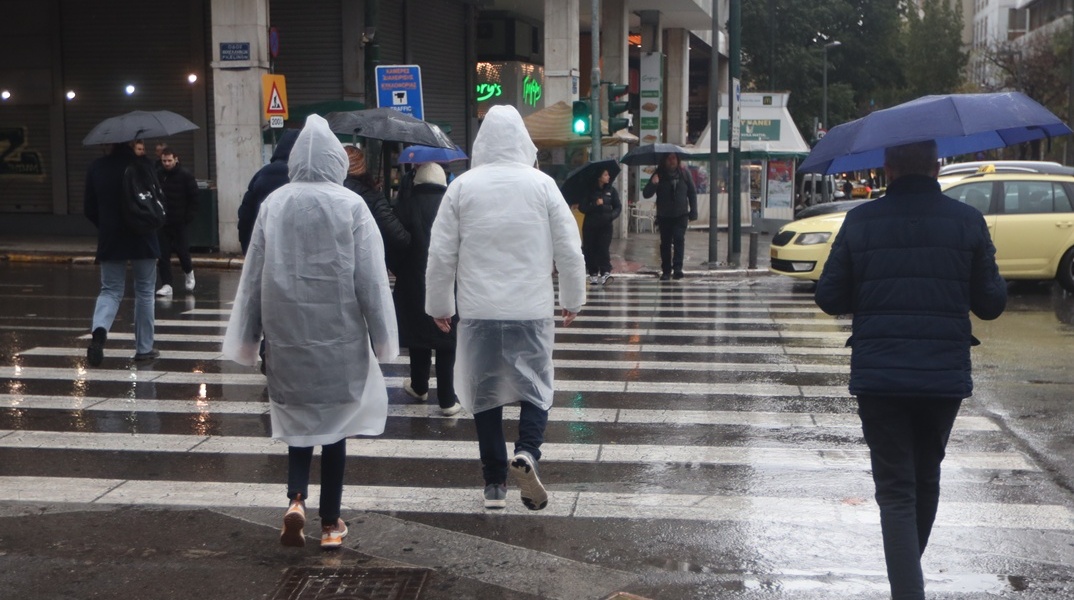 Πολίτες με ομπρέλες εν μέσω καταιγίδας στην Αττική