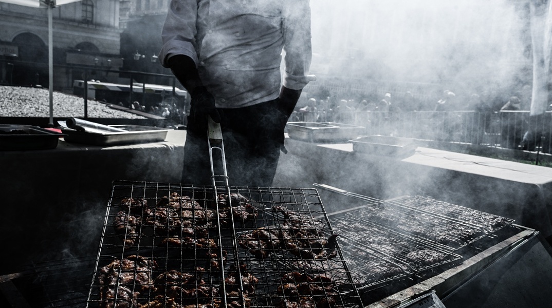 Άτομο ψήνει σε σκάρα και κάρβουνα  κρέας