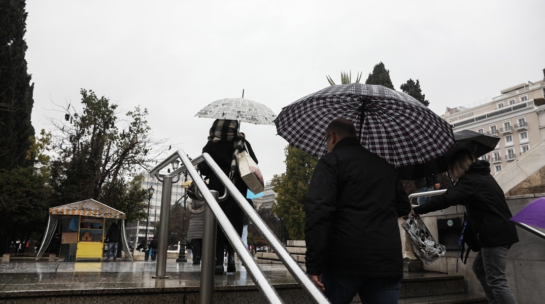 Πολίτες εν μέσω καταιγίδας έξω από τον σταθμό του μετρό στο Σύνταγμα