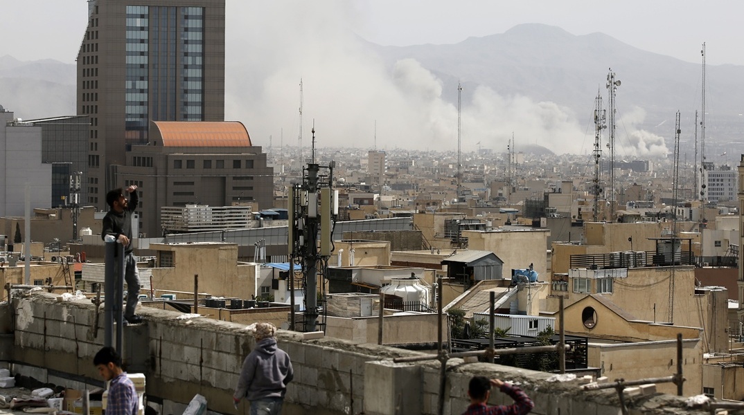 Πολίτες στις ταράτσες σπιτιών στην Τεχεράνη παρακολουθούν τους καπνούς από τα πλήγματα των ΗΠΑ και του Ισραήλ