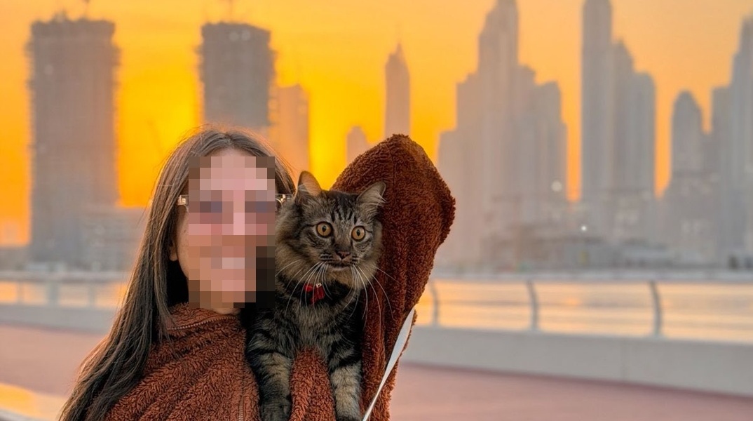 Γυναίκα με γατούλα στον ώμο με φόντο το Ντουμπάι