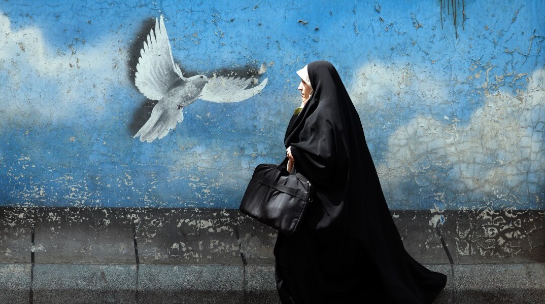 Γυναίκα στην Τεχεράνη, την πρωτεύουσα του Ιράν, περνά μπροστά από mural που δείχνει ένα περιστέρι να πετά