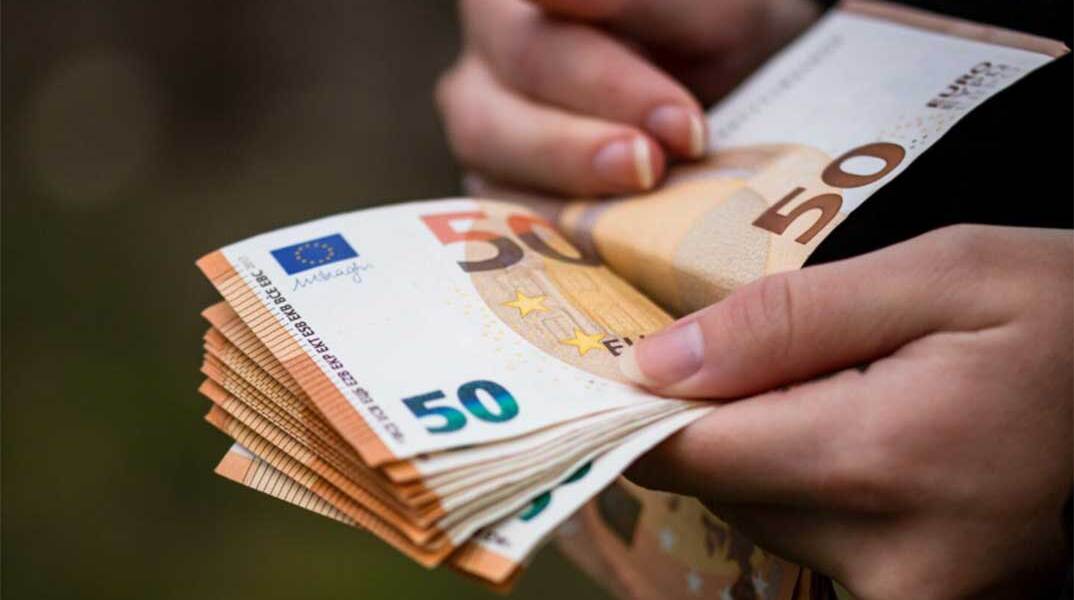 Άνδρας μετρά χαρτονομίσματα του ευρώ