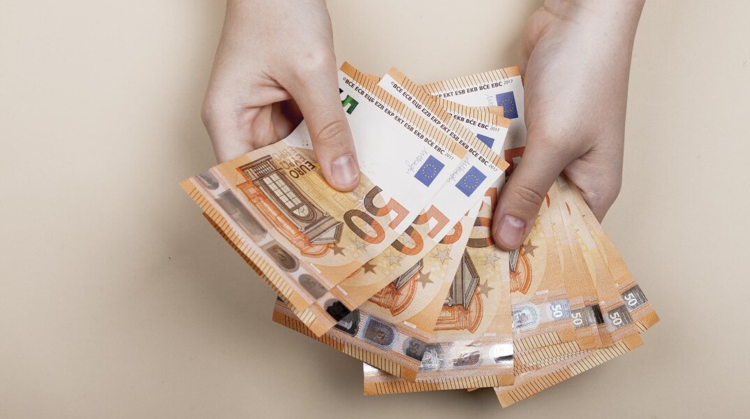 Άνδρας κρατά χαρτονομίσματα των 50 ευρώ