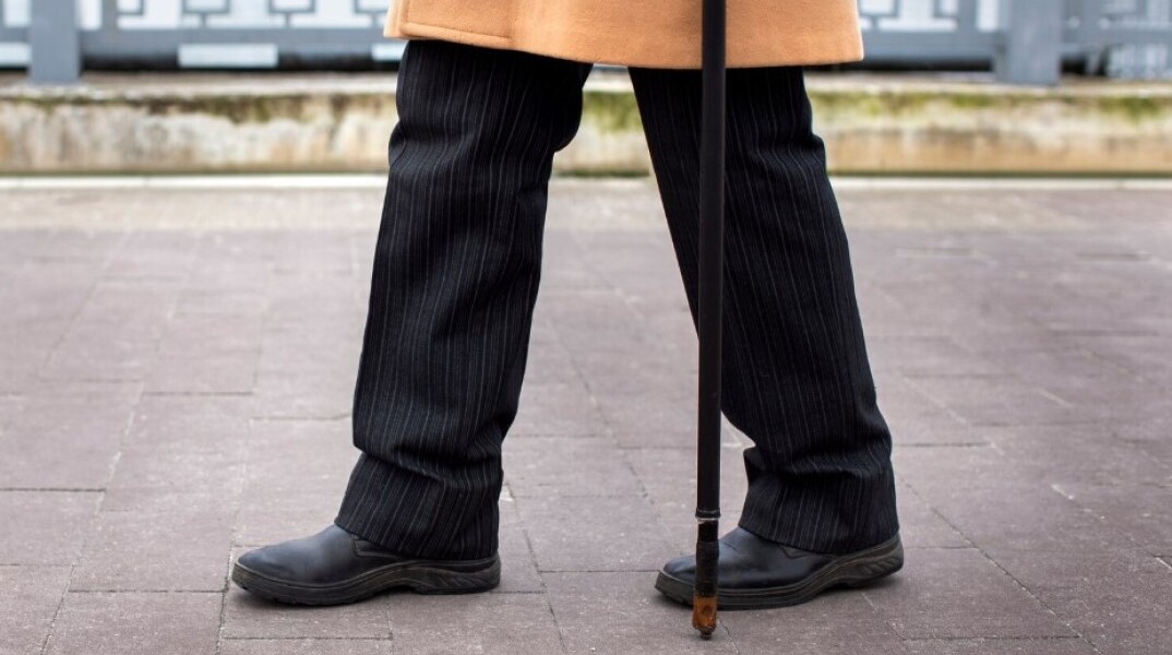 Συνταξιούχος περπατά με μπαστούνι στην πόλη