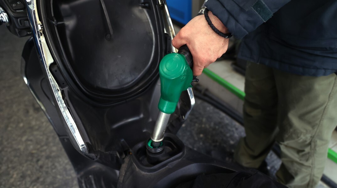 Υπάλληλος σε πρατήριο υγρών καυσίμων βάζει βενζίνη στη μηχανή