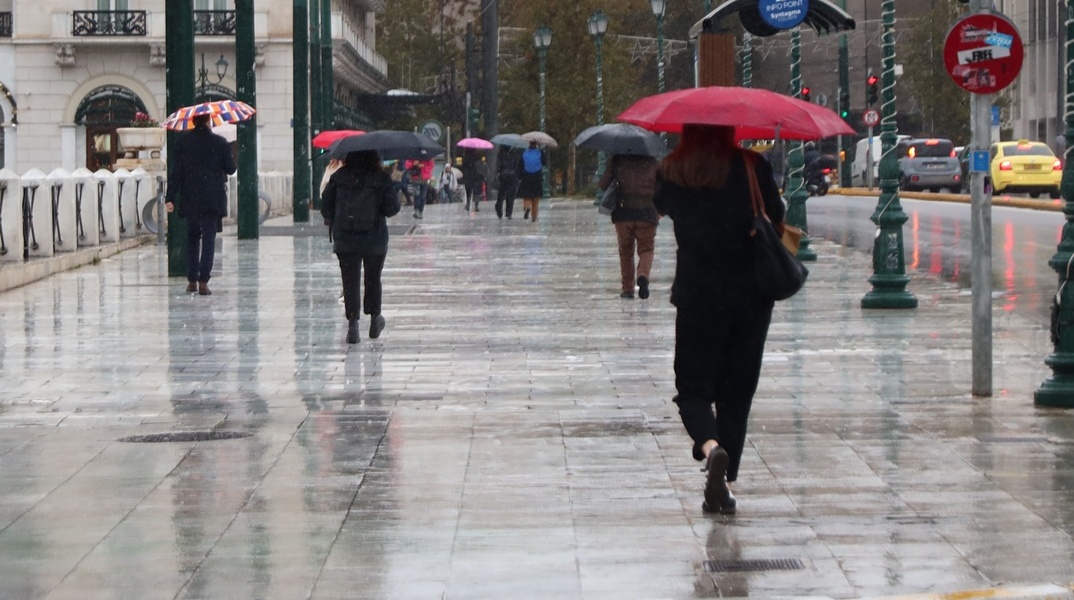 Άτομα με ομπρέλα εν μέσω καταιγίδας στην Αθήνα