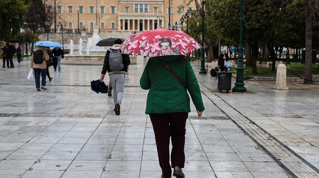 Πολίτες με ομπρέλες εν μέσω βροχής στο Σύνταγμα
