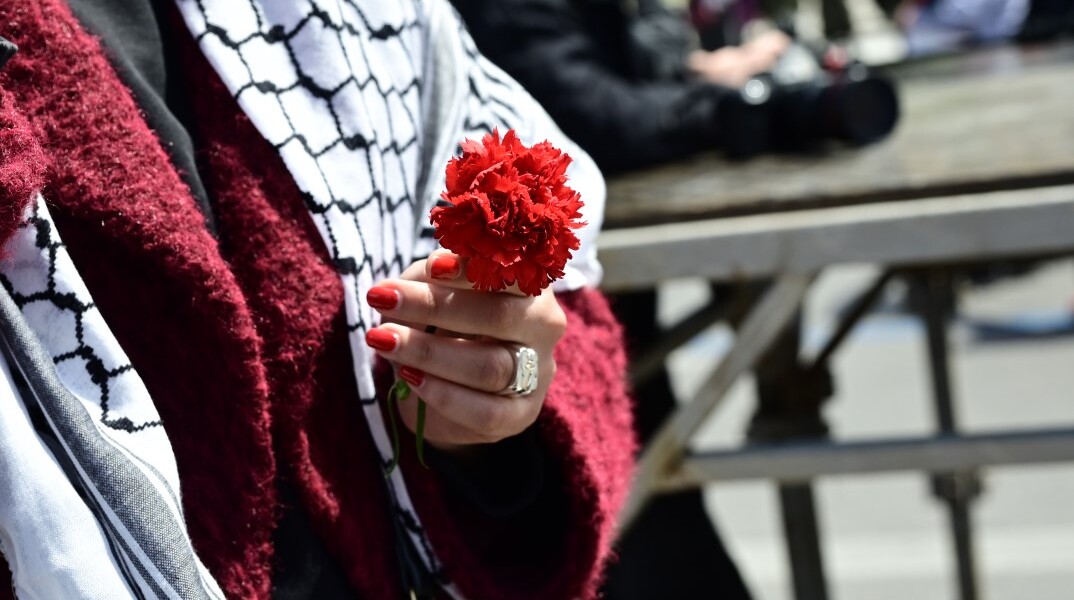 Γυναίκα κρατά κόκκινο γαρύφαλλο για την Πρωτομαγιά