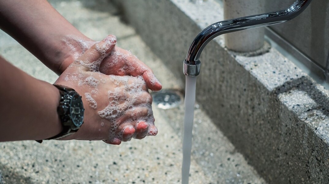 Νεαρός πλένει τα χέρια του με νερό και σαπούνι στη βρύση