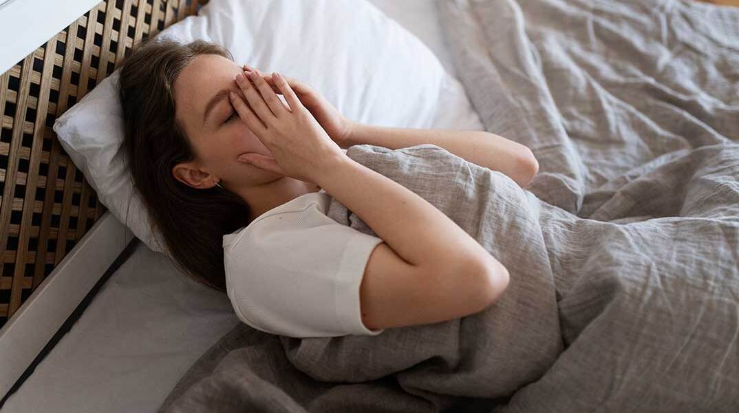 Γυναίκα στη μία πλευρά του κρεβατιού δυσκολεύεται να κοιμηθεί