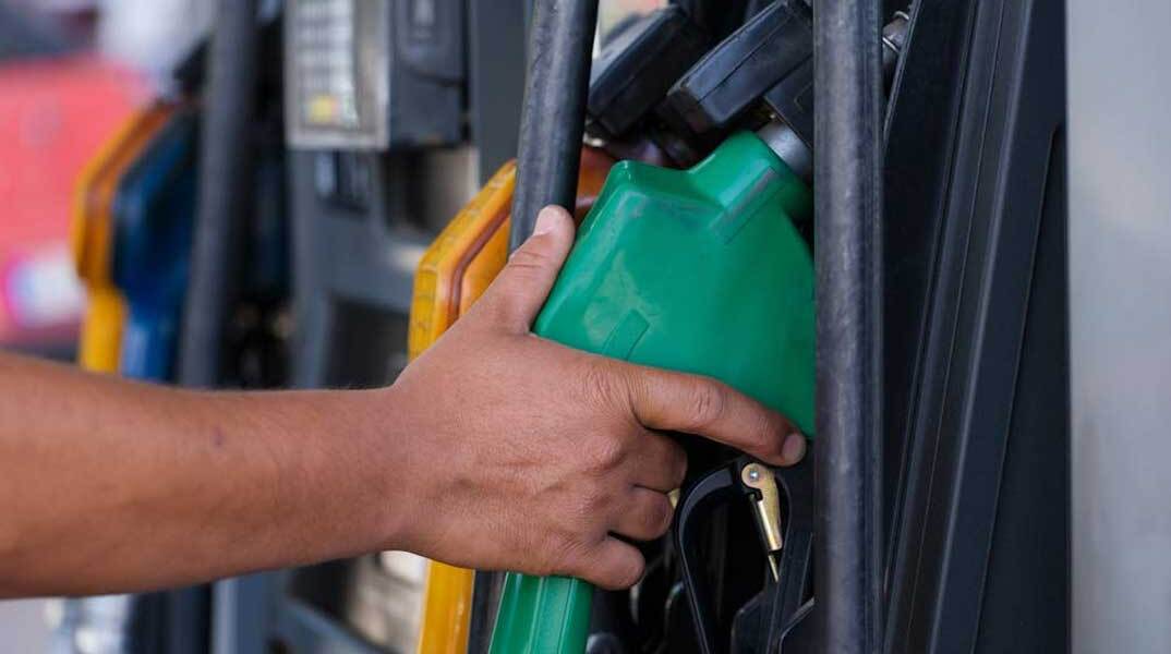 Υπάλληλος σε βενζινάδικο πιάνει την αντλία για να γεμίσει βενζίνη το ρεζερβουάρ του αυτοκινήτου