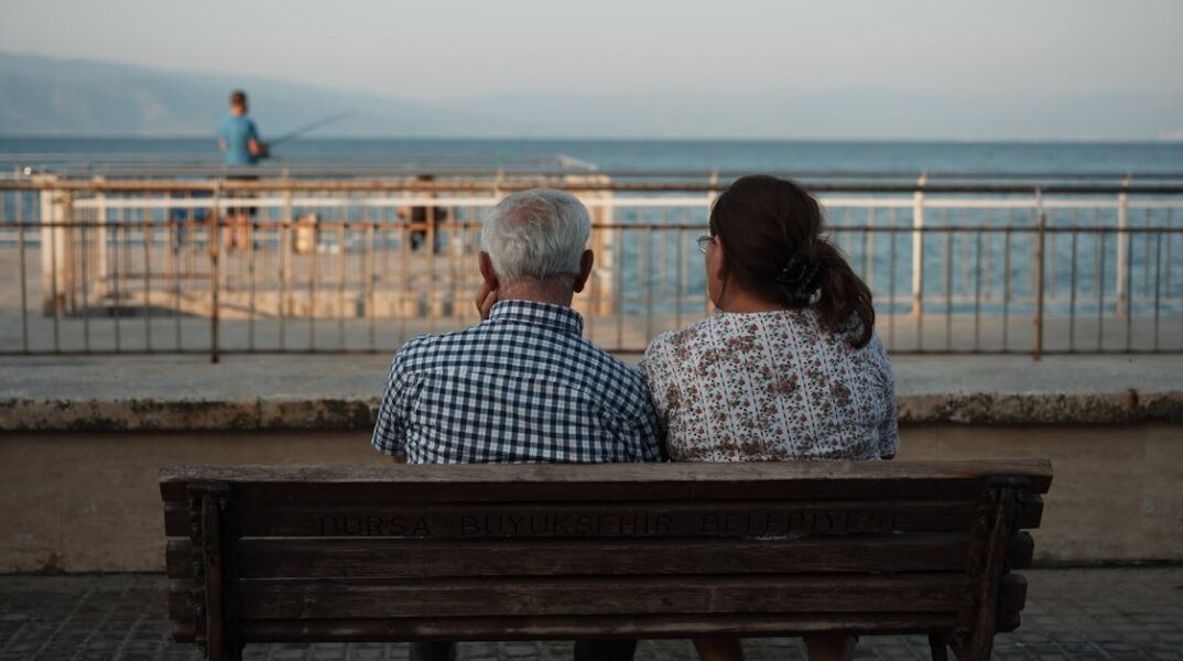 Συνταξιούχοι, καθισμένοι σε παγκάκι, κοιτούν τη θάλασσα