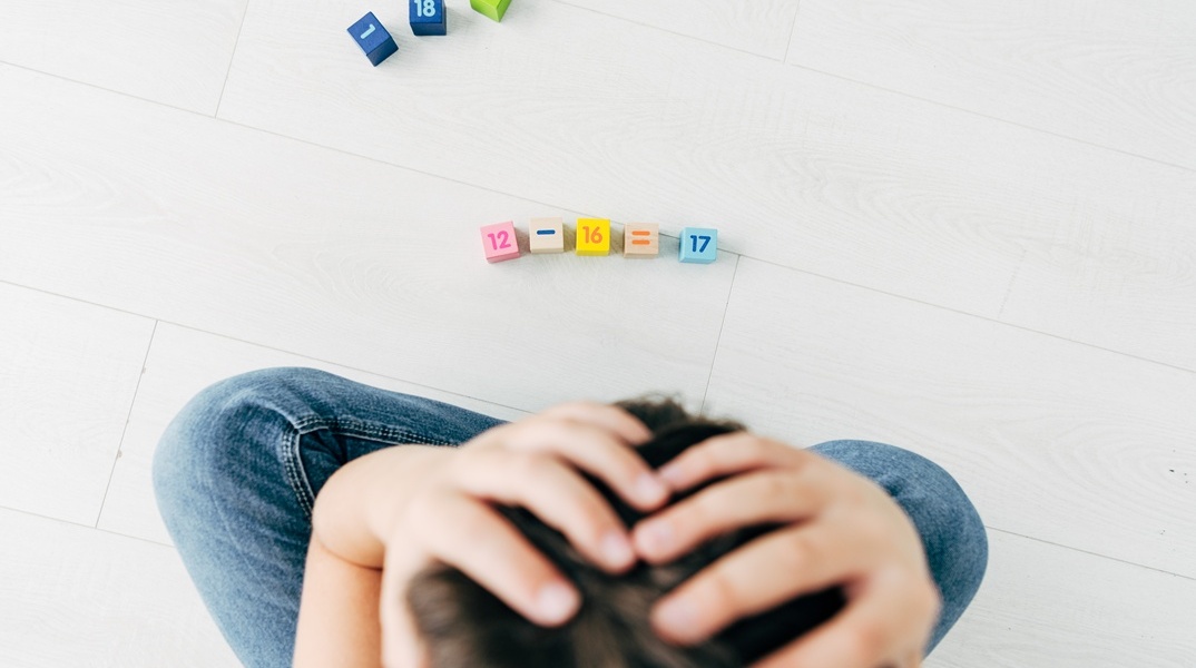 Παιδί που απελπίζεται κάνοντας υπολογισμούς αριθμητικής με τουβλάκια