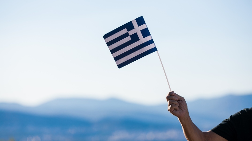 Χέρι κρατά ελληνική σημαία