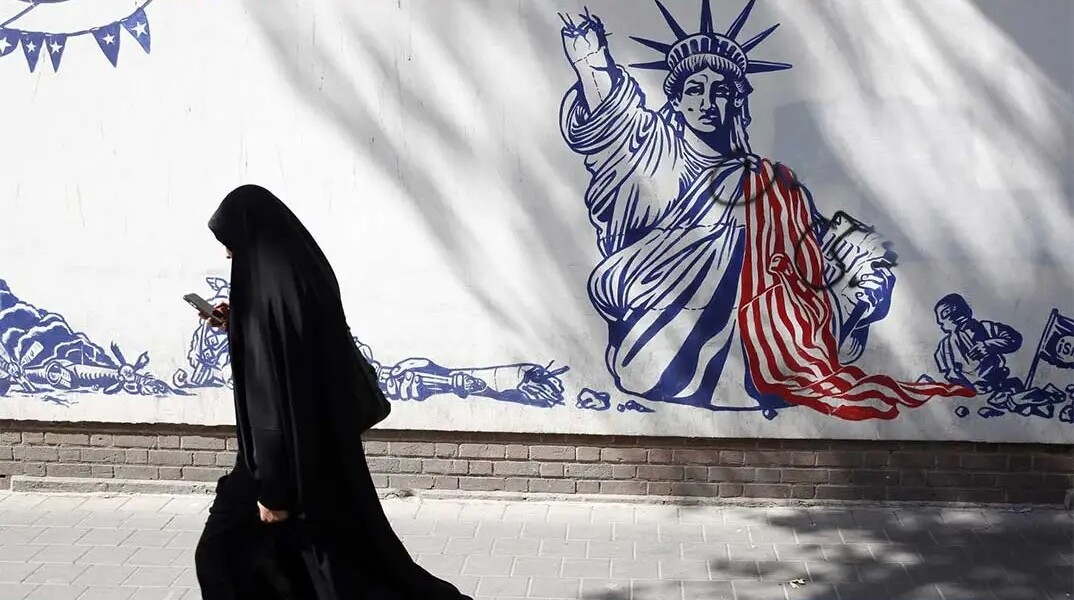 Γυναίκα περνά μπροστά από mural στην Τεχεράνη για τον πόλεμο Ιράν με ΗΠΑ