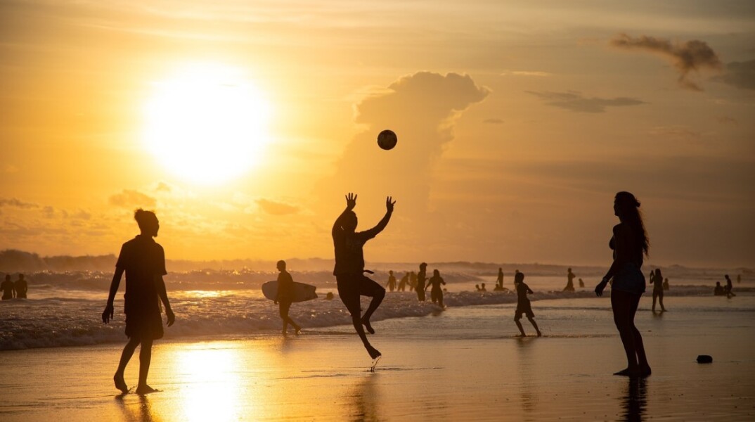 Λουόμενοι στην παραλία με φόντο το ηλιοβασίλεμα