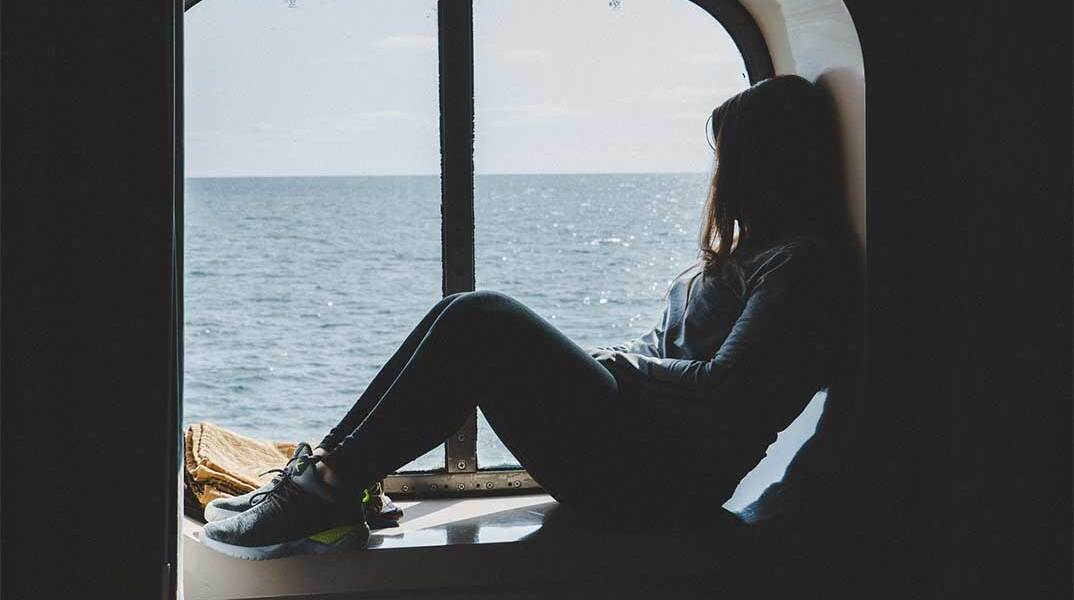 Επιβάτης μέσα σε πλοίο κάθεται μπροστά στο παράθυρο καμπίνας
