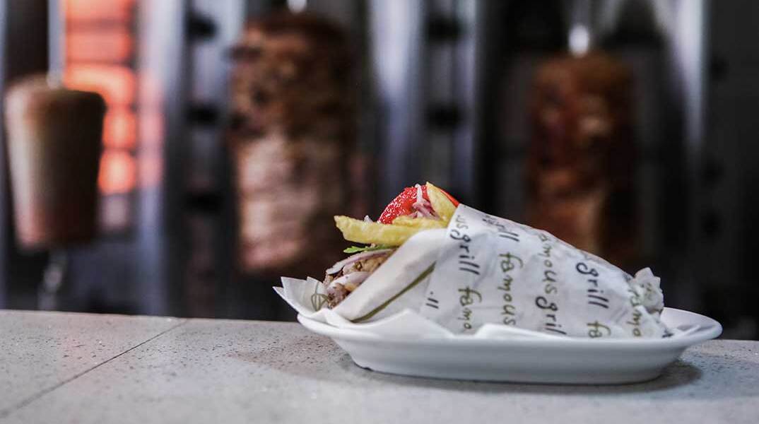 Σουβλάκι σε πάγκο ψητοπωλείου με φόντο τον γύρο