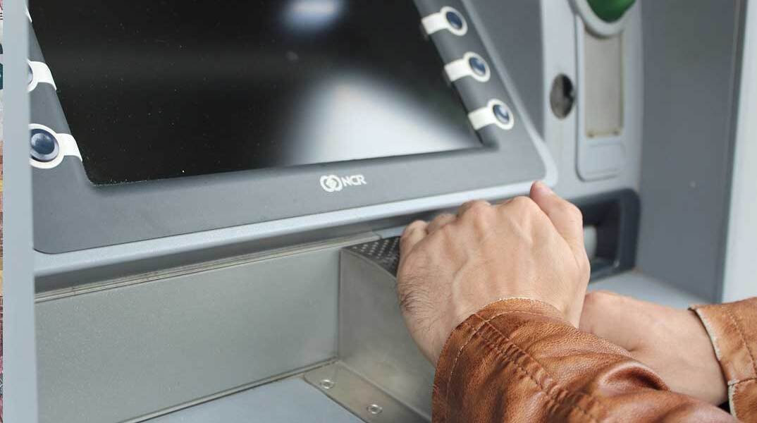 Συνταξιούχος πληκτρολογεί το PIN σε ΑΤΜ